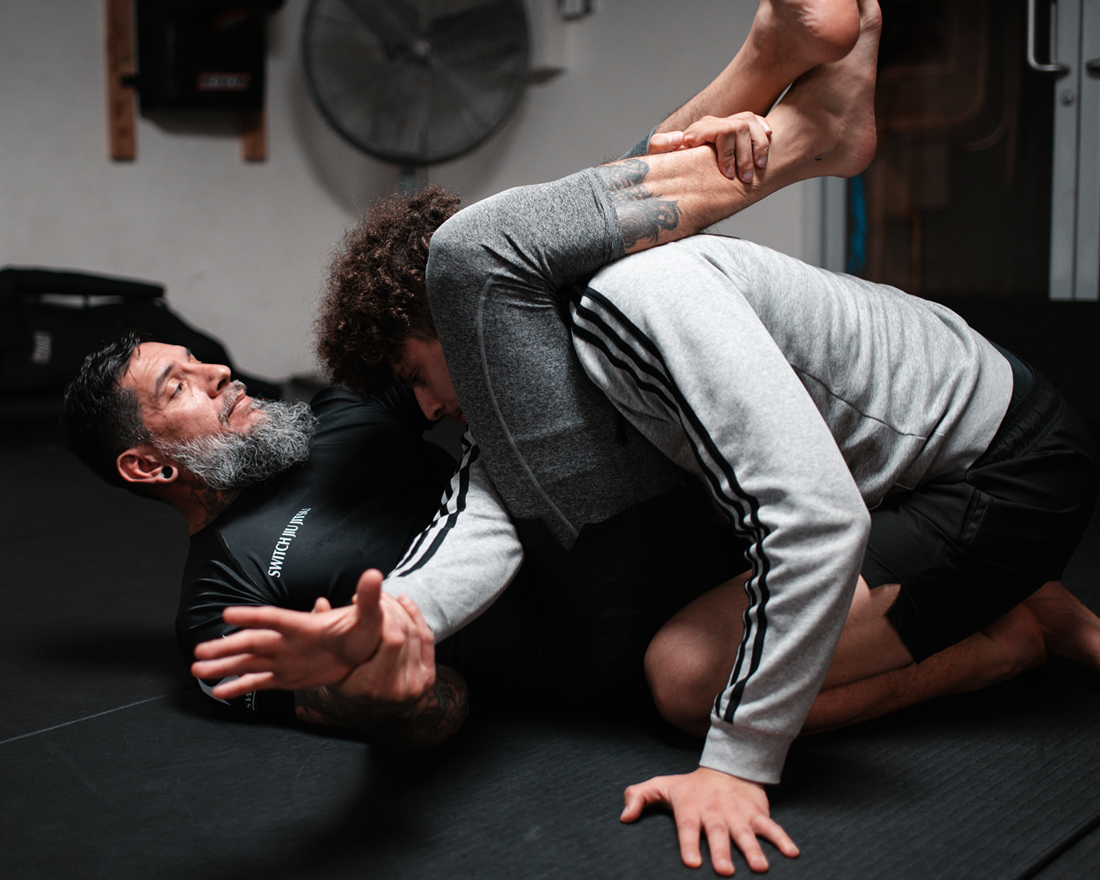 Two students drilling a Jiu Jitsu position on the mat at Switch Fitness San Diego.