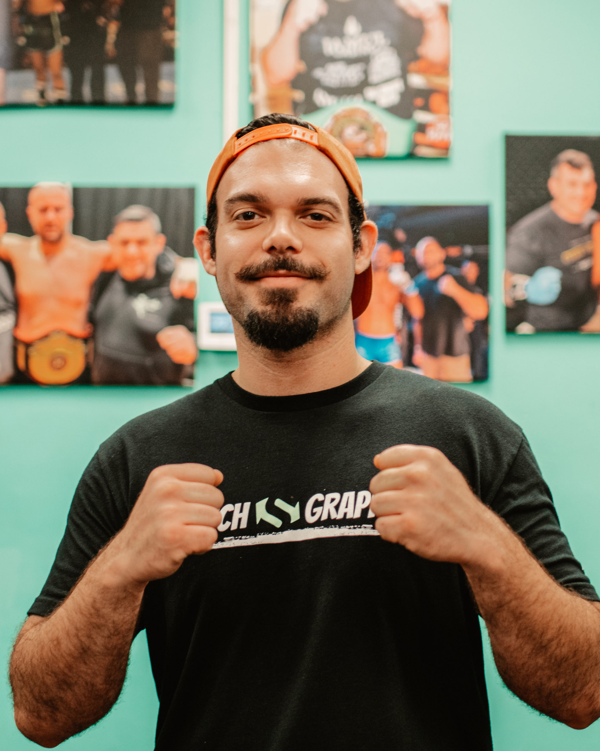 A member standing in front of the gym's wall of fight photos at Switch Fitness San Diego.